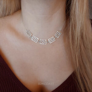 a silver necklace on a wood surface